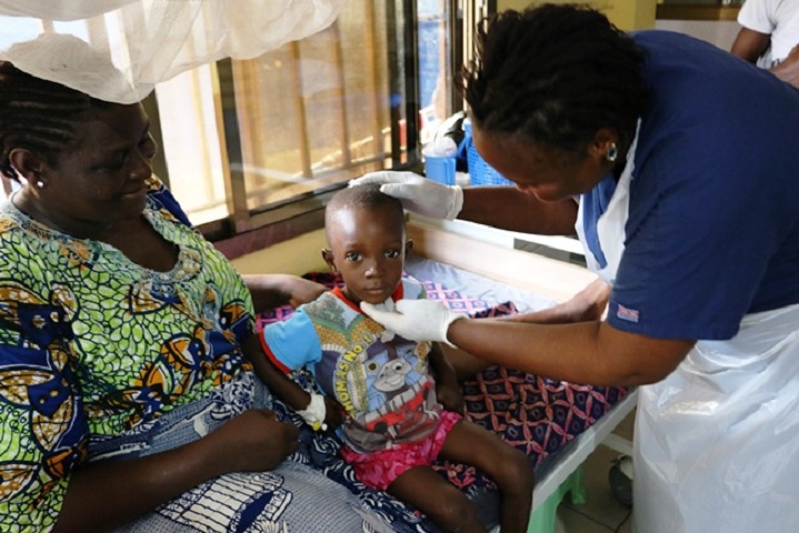 selective focus of curly african american child holding dirty medical mask near poor brother sitting